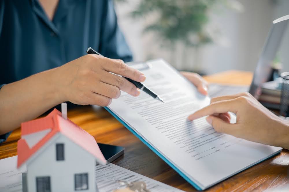 closeup of a broker presenting a loan contract on a clipboard and going over the terms