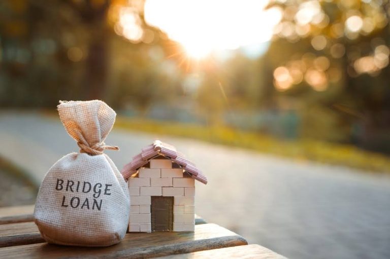 small sack with the words “bridge loan” written on it next to a small model home